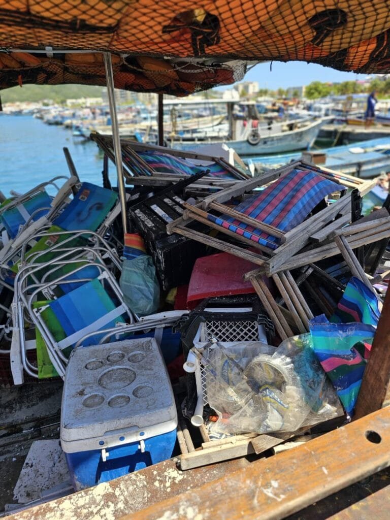 Agentes da Prefeitura removendo cadeiras e equipamentos de praia armazenados irregularmente na areia da Praia do Forno.