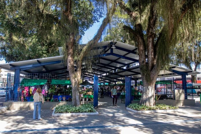 Vista externa da nova cobertura da Feira da Agricultura Familiar de Macaé com estrutura moderna e visitantes circulando pelo local.