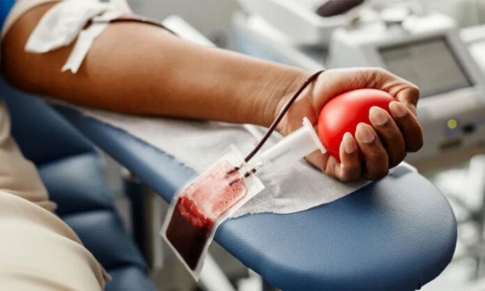 Foto de braço de um doador fazendo a coleta de sangue num ambiente próprio para o procedimento.