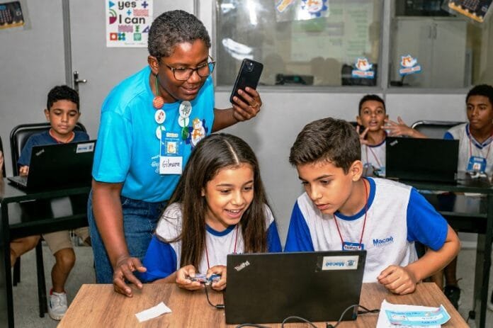 Macaé se destaca no Saeb e registra avanços na rede municipal de ensino Crianças na escola aprendendo no computador com auxilio do professor