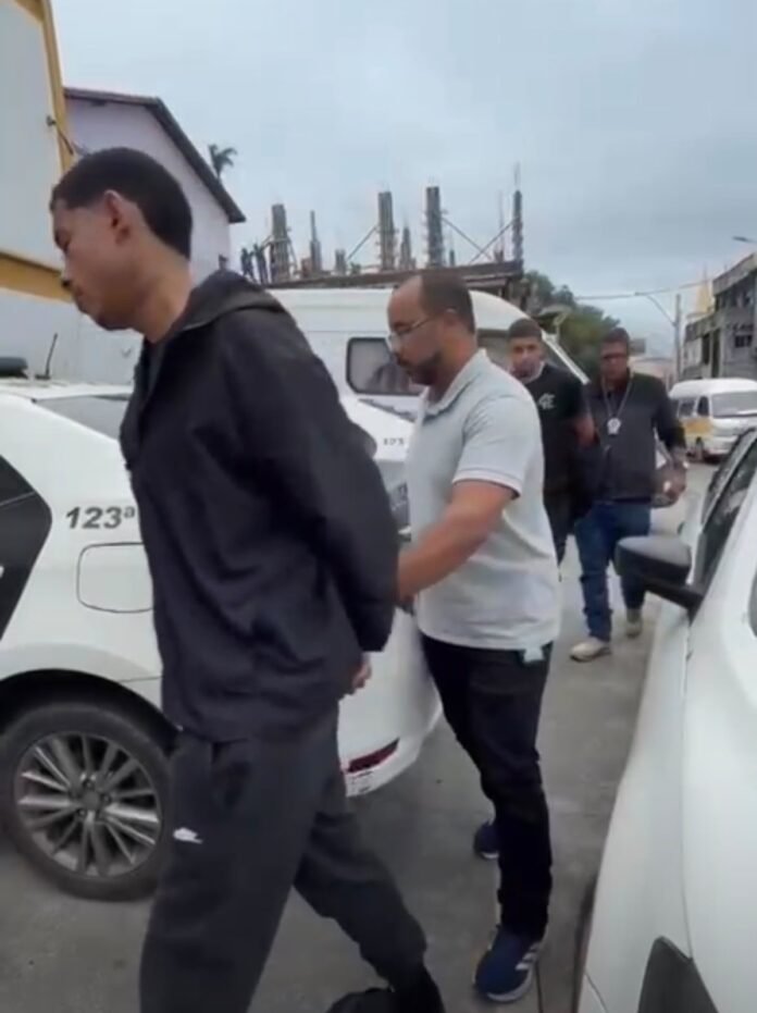 Agentes da delagacia conduzindo suspeito à viatura