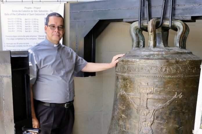 Foto do sino e o padre Arthur Torre